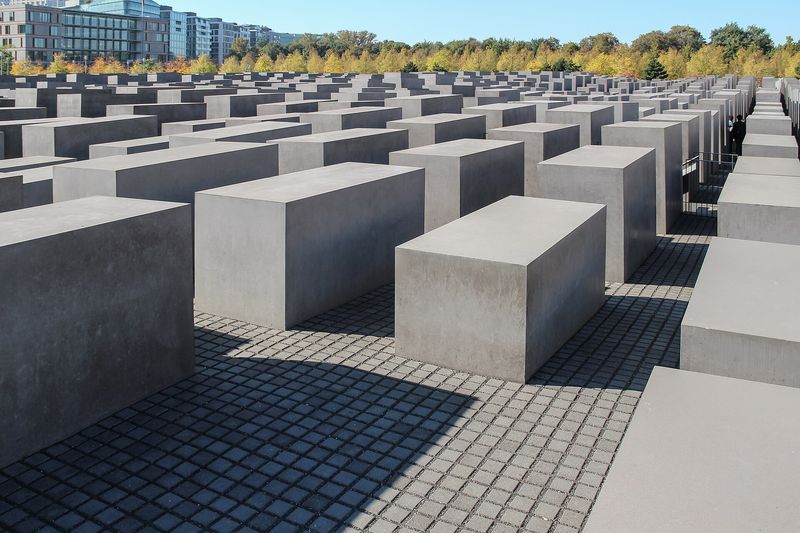 Die grauen Betonstelen des Denkmals für die ermordeten Juden Europas in unterschiedlichen Höhen, dahinter Bäume im Herbstlaub