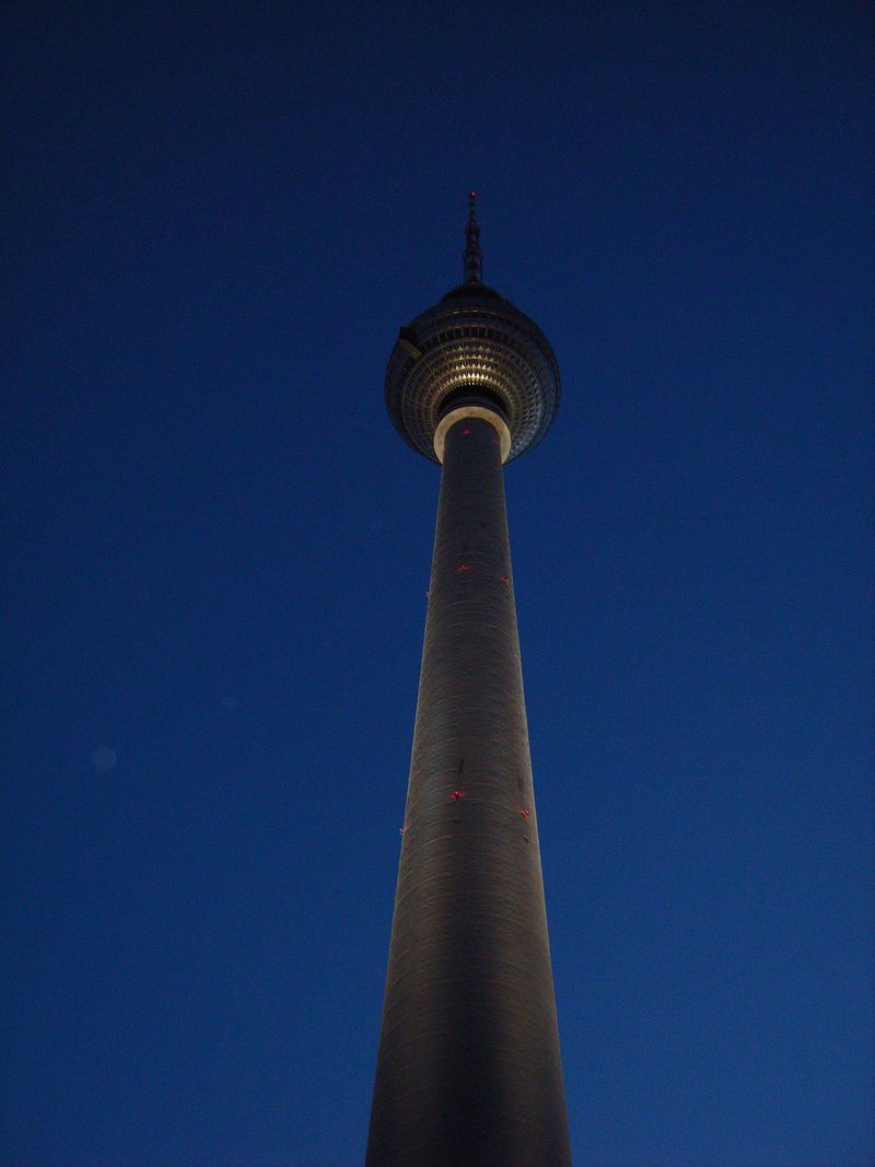 Der Schaft des Fernsehturms mit der Turmkugel, steil von unten fotografiert vor tiefblauem Himmel in der Dämmerung