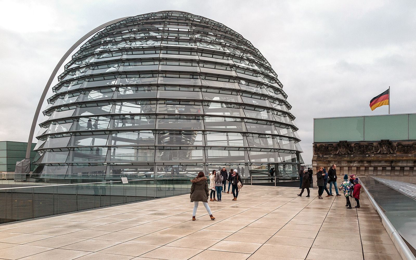 Die gläserne Kuppel auf dem Dach des Reichstagsgebäudes, davor Besucherinnen und Besucher auf der Dachterrasse